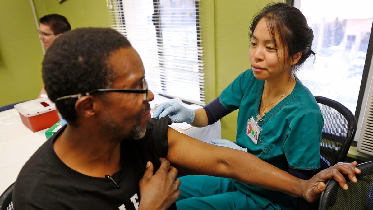 Carolyn Angela Chen, a registered nurse with Los Angeles Christian Health Centers, gives a free hepatitis A vaccination to Glenn Gardner, 52, at Joshua House Clinic on Skid Row.