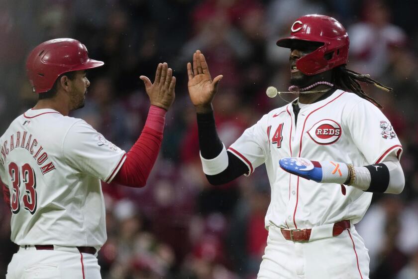 El dominicano Elly de la Cruz, de los Rojos de Cincinnati, festeja con su compañero Christian Encarnación-Strand, tras anotar en el juego del martes 23 de abril de 2024 (AP Foto/Carolyn Kaster)