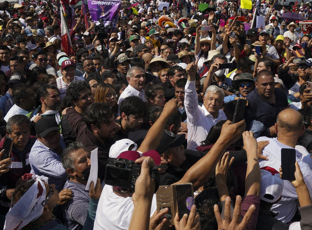 Mexican President Andrés Manuel Lopez Obrador is surrounded by supporters during a march in in Mexico City.