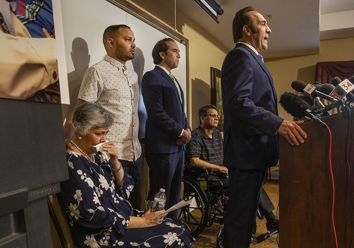 An attorney at a podium announces a suit.