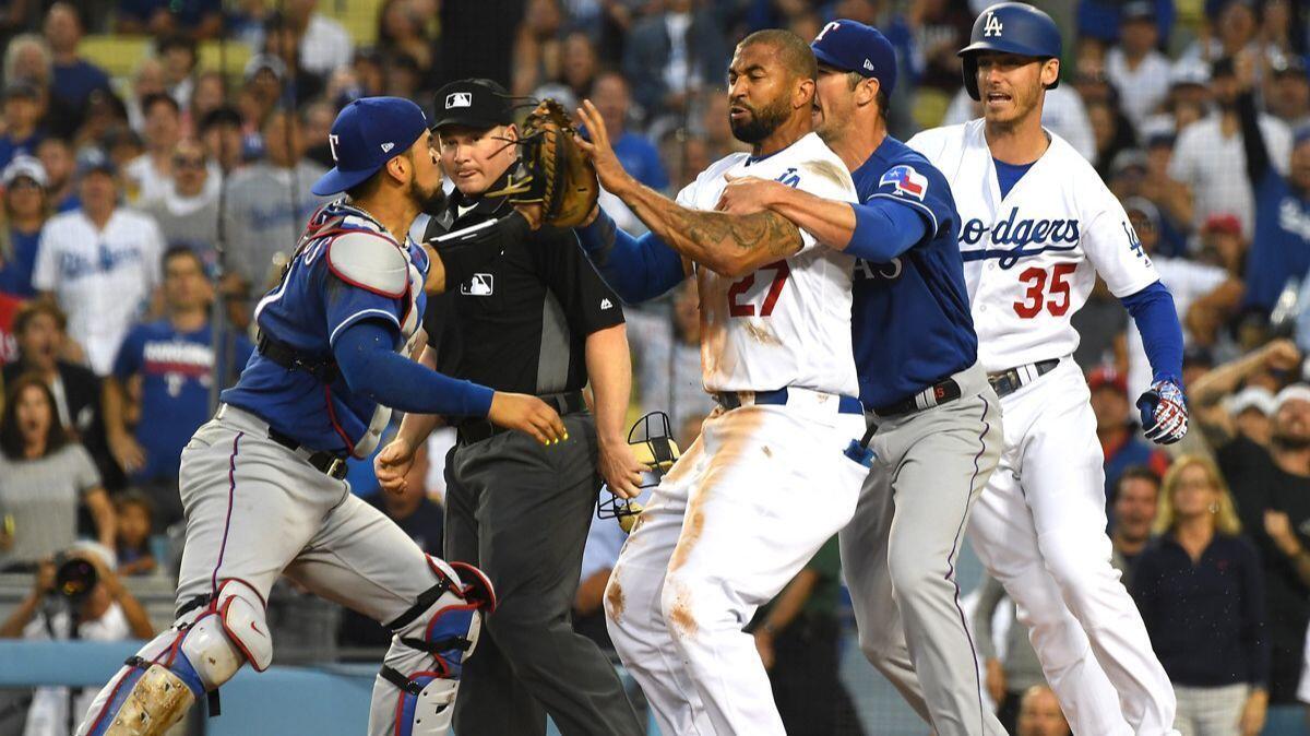 Texas Rangers' Cole Hamels (35) and Dodgers' Cody Bellinger (35) try to hold back Matt Kemp (27) and Robinson Chirinos (61) as tempers flared after a collision at home plate in the third inning.