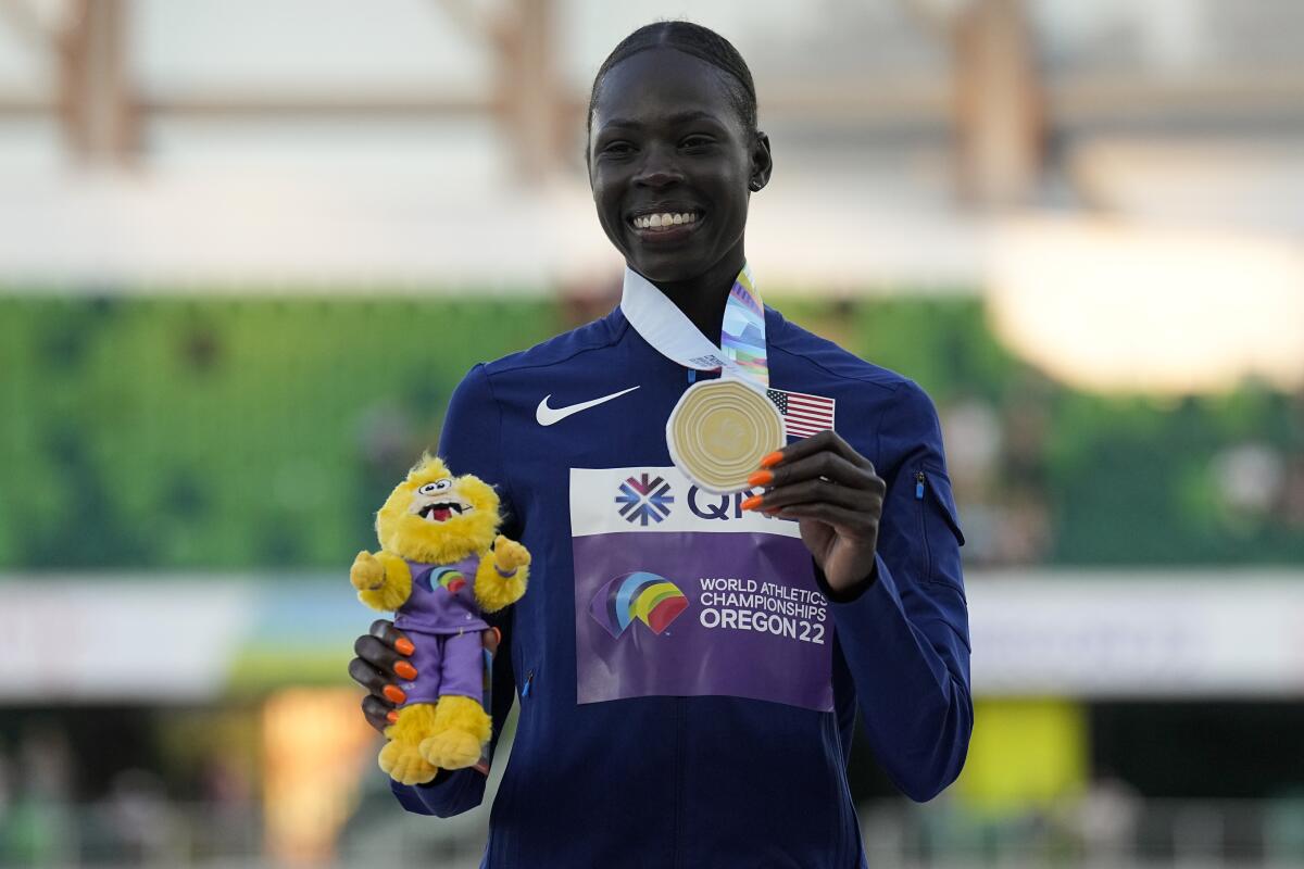 Athing Mu holds her gold medal and a stuffed animal.