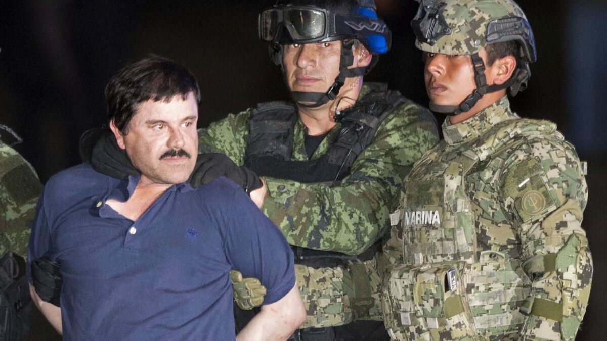 Joaquin "El Chapo" Guzman is forced to face the press as he is escorted to a helicopter in handcuffs by Mexican soldiers in 2016.
