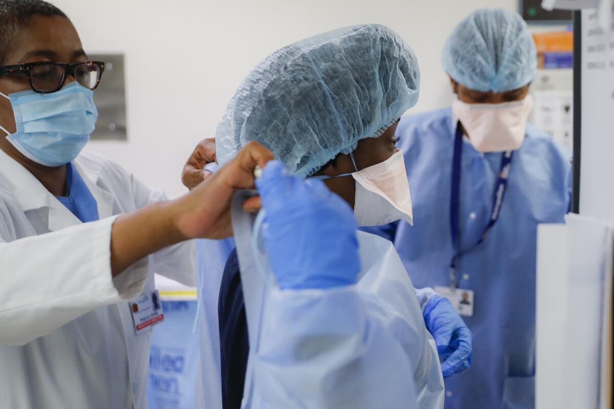 Medical personnel adjust personal protective equipment 