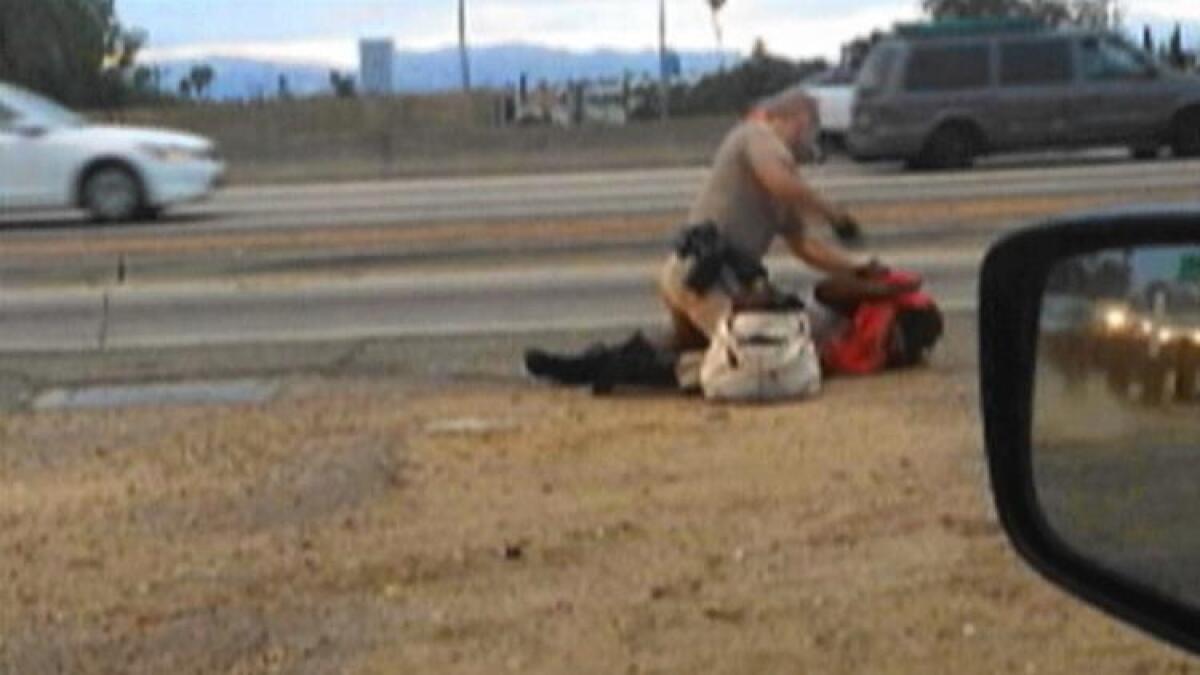 A California Highway Patrol officer straddles a woman on the shoulder of the 10 Freeway. The July 1 incident has raised questions about law enforcement's training to handle some crisis situations.