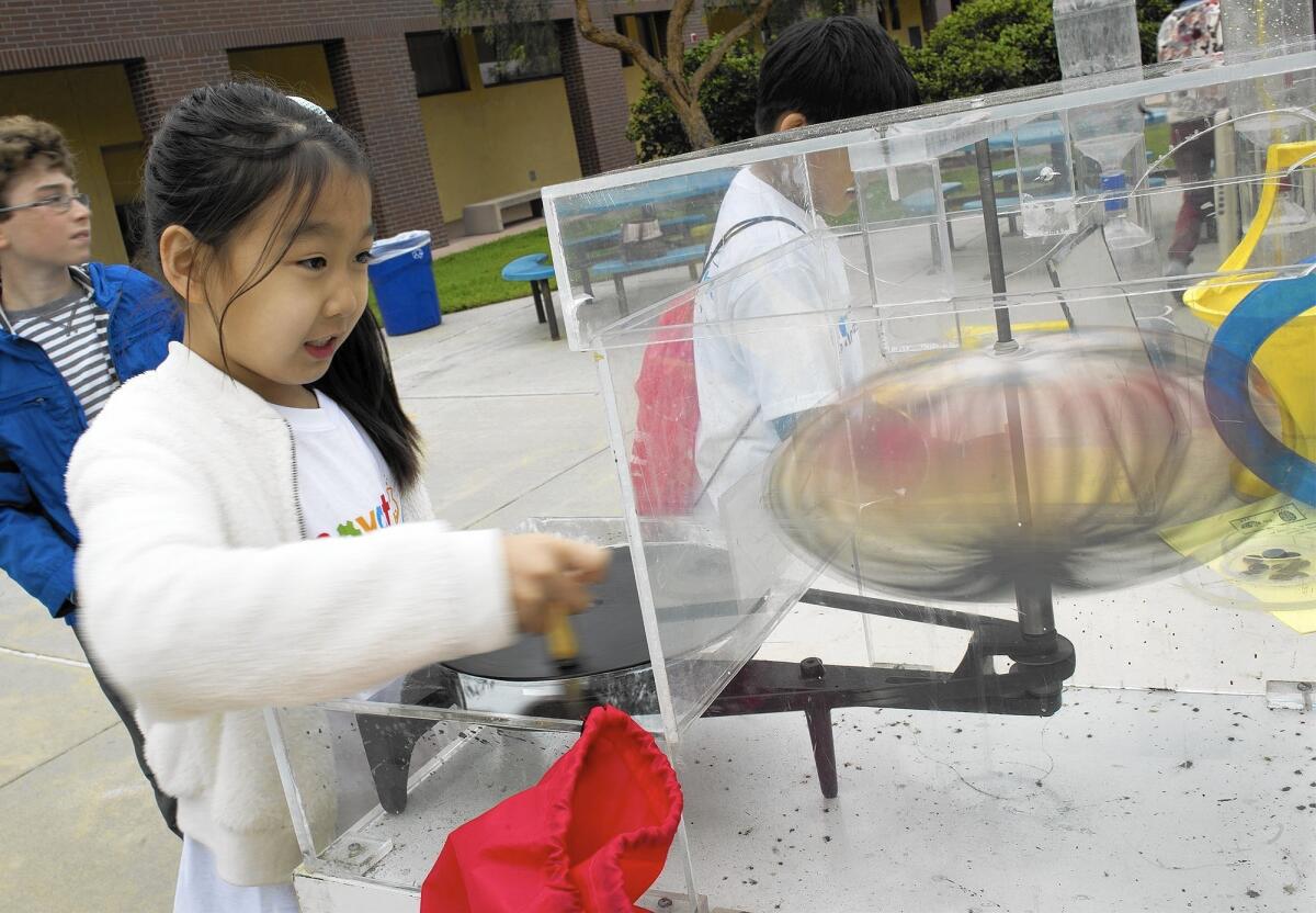 Third-grader Ellie Chang, 8, of College Park Elementary School watches a sphere, representing the planet Saturn, change shapes as she cranks a wheel in circles.