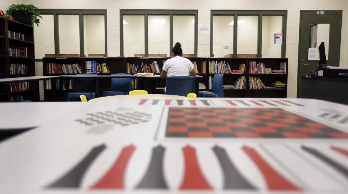 In this 2014 file photo, a woman uses the library at the Karnes County Residential Center, a temporary home in Karnes City, Texas, for immigrant women and children detained after crossing U.S.-Mexico border illegally.