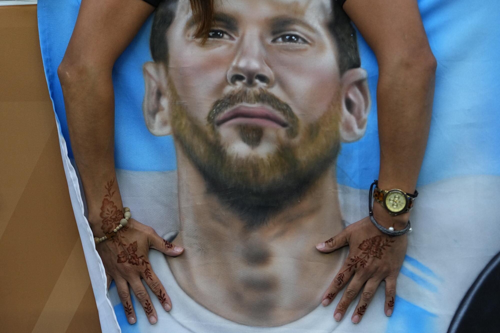 An Argentinian places a poster of their star player Lionel Messi's before the World Cup final.