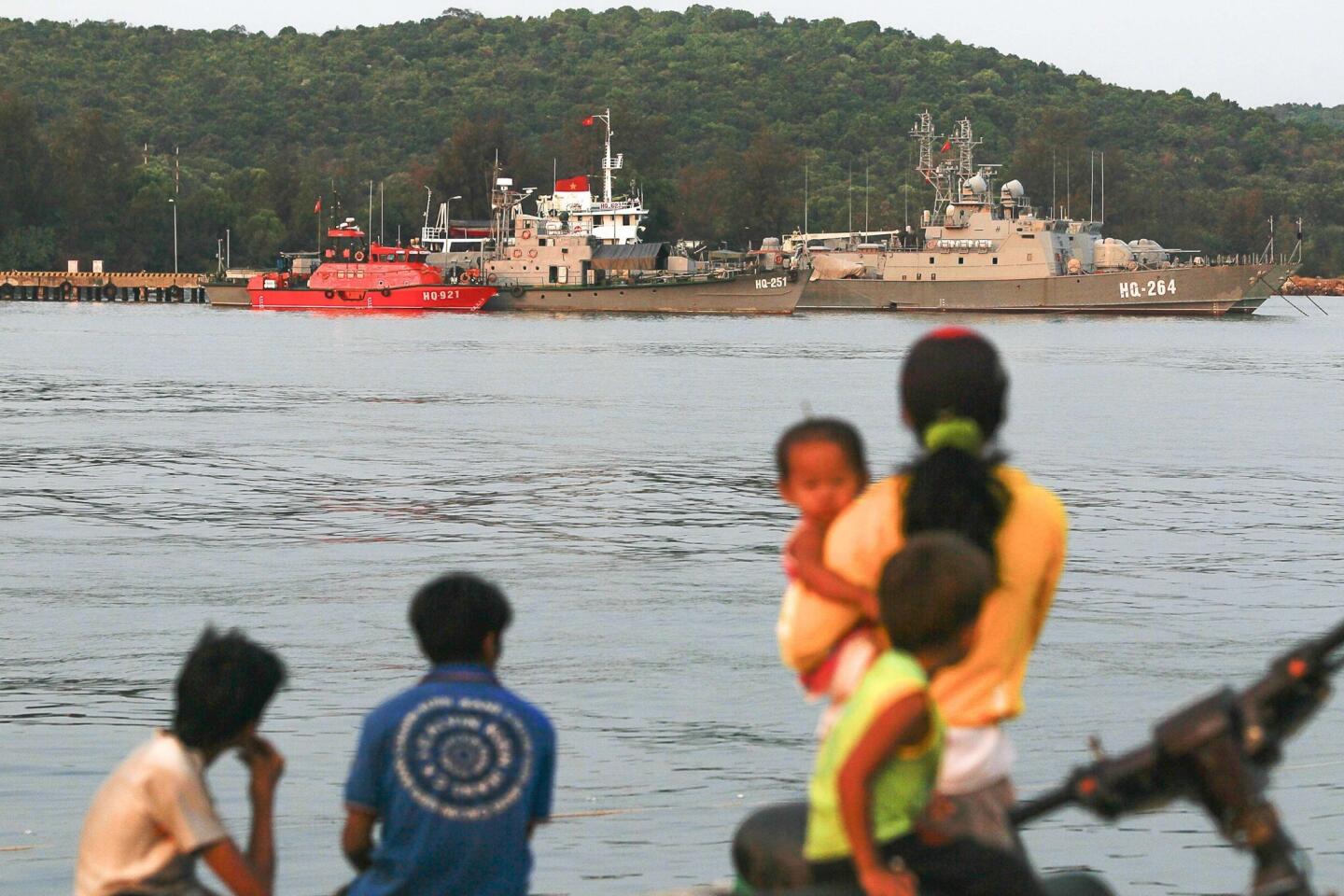 Residents look at ships anchored at a local naval base at Phu Quoc island, in the waters of southern Vietnam, where a Malaysian Airlines jet was presumed lost.