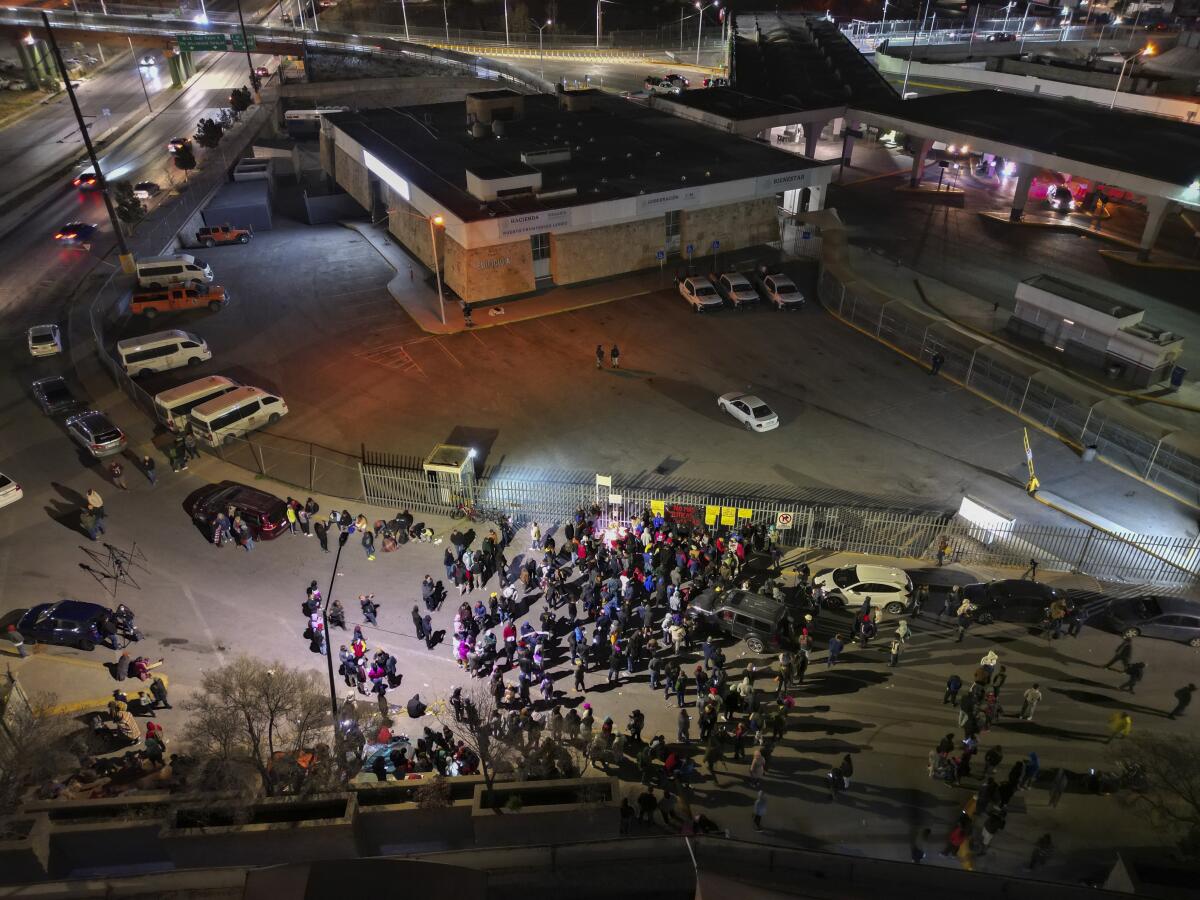 An overhead view of people gathered at night outside a large building 