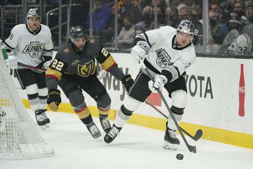 Los Angeles Kings defenseman Tobias Bjornfot (7) controls the puck ahead of Vegas Golden Knights center Michael Amadio (22) during the first period of an NHL hockey game Tuesday, Dec. 28, 2021, in Los Angeles. (AP Photo/Ashley Landis)