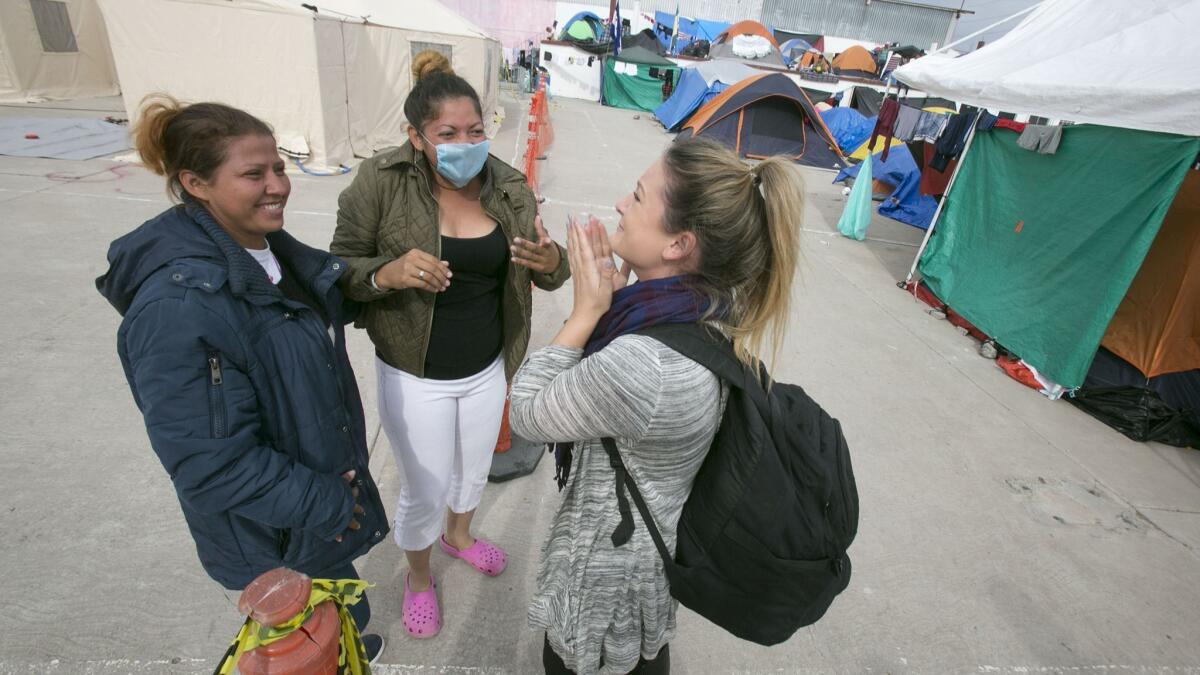 San Diego resident Amy Tillman, right, reacts as she greets Honduran caravan members Iris Hernandez, left, and Paola Martinez, center, at the El Barretal shelter in the Mariano Matamoros section of Tijuana.