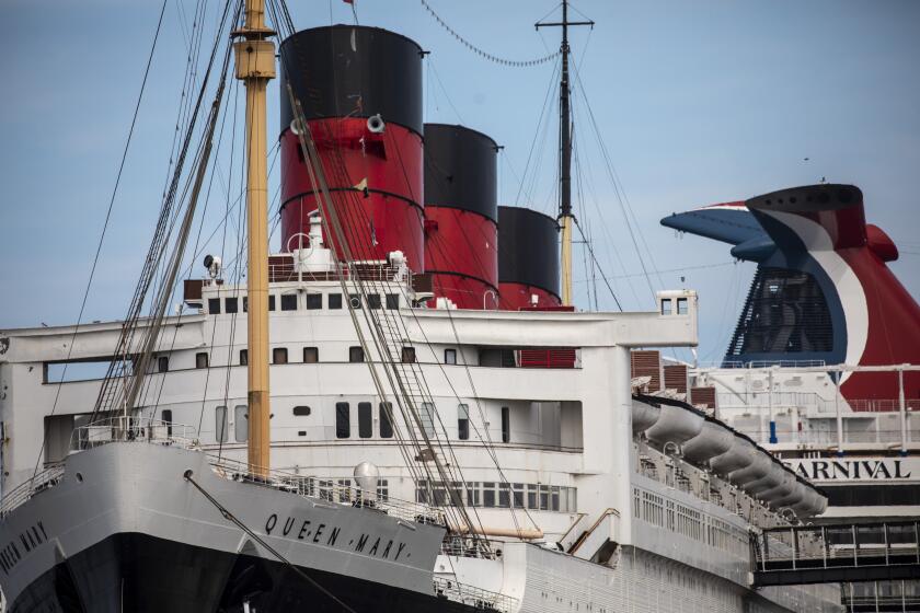 Long Beach, CA - May 25: A view of the Queen Mary ship, with a modern Carnival Cruise ship behind, docked in Long Beach, CA, photographed Tuesday, May 25, 2021. The ship has been a tourist destination and hotel for years and is now in danger of capsizing according to a recent inspection report. (Jay L. Clendenin / Los Angeles Times)