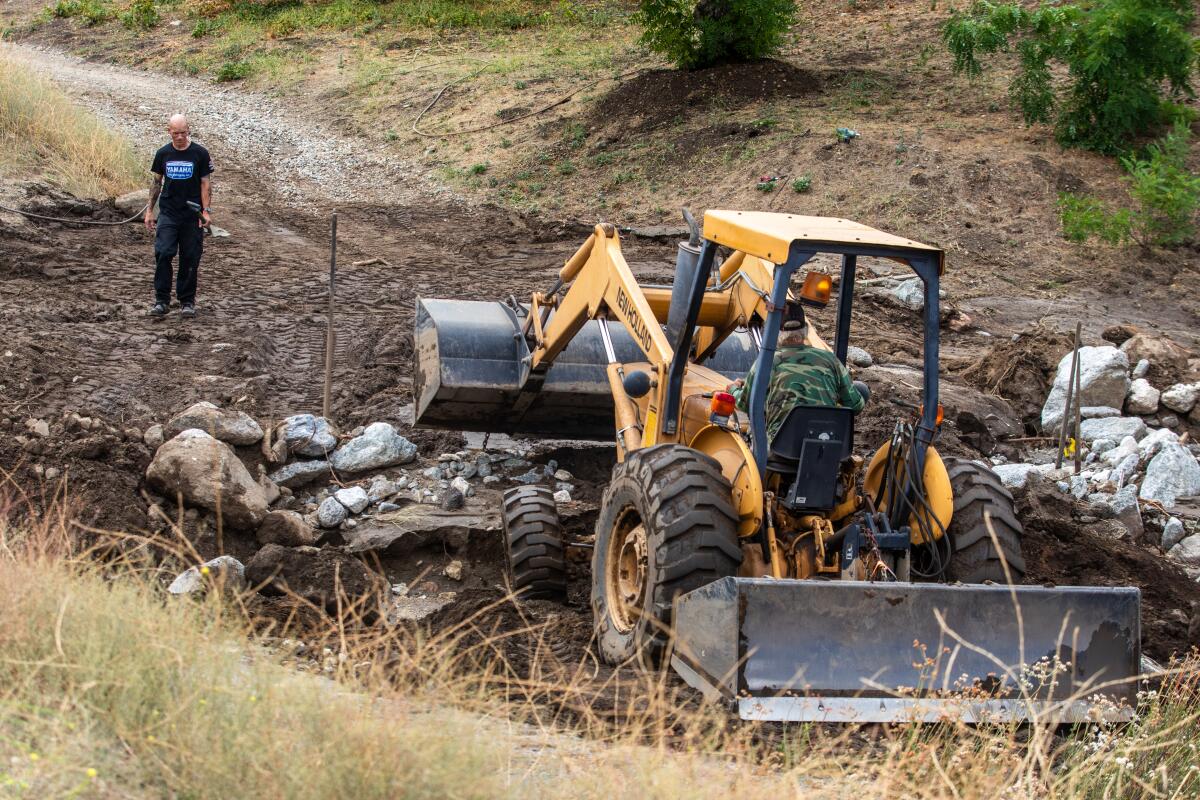 Bryan Dodge Jr., 44, left, is helping his father, Bryan Dodge Sr., 68, move mud and debris