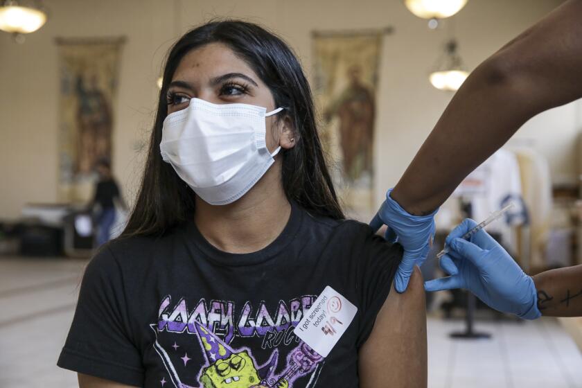 Los Angeles, CA - April 09: Cecy Gonzalez, 20, gets a COVID-19 vaccine at a vaccination clinic established by Councilman Curren Price in partnership with St. John's Well Child and Family Center at St. Patrick's Catholic Church on Friday, April 9, 2021 in Los Angeles, CA.(Irfan Khan / Los Angeles Times)