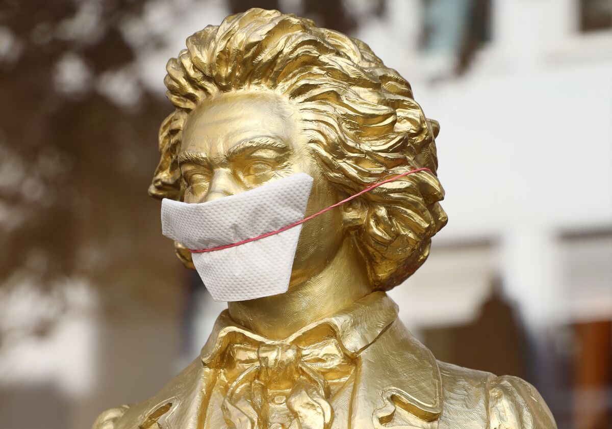In Bonn, Germany, a bust of Beethoven gets a mask. Germany's jobless benefit pays 60% of a worker's salary for a year.