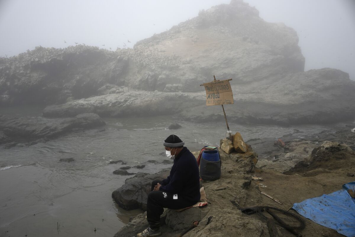 FILE - Fisherman Walter de la Cruz sits on the shore of the oil-stained Cavero Beach, unable to fish after a spill in the Ventanilla district of Callao, Peru, Jan. 21, 2022. De la Cruz, 60, is one of more than 2,500 fishermen whose livelihoods have been cast into doubt as a result of a large crude-oil spill by the Spanish-owned Repsol oil refinery on Jan. 15. (AP Photo/Martin Mejia, File)