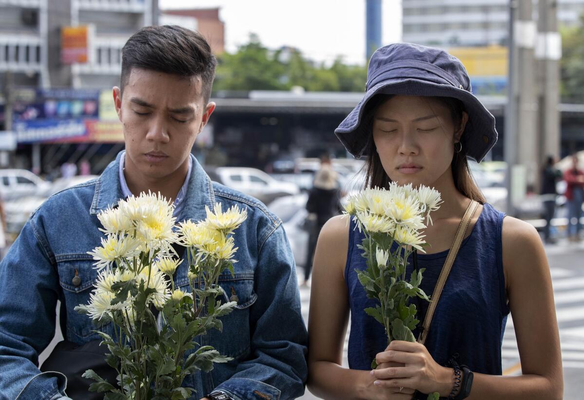 A couple offers flowers at the scene of a mass shooting outside the Terminal 21 shopping mall in Nakhon Ratchasima, Thailand, on Monday.