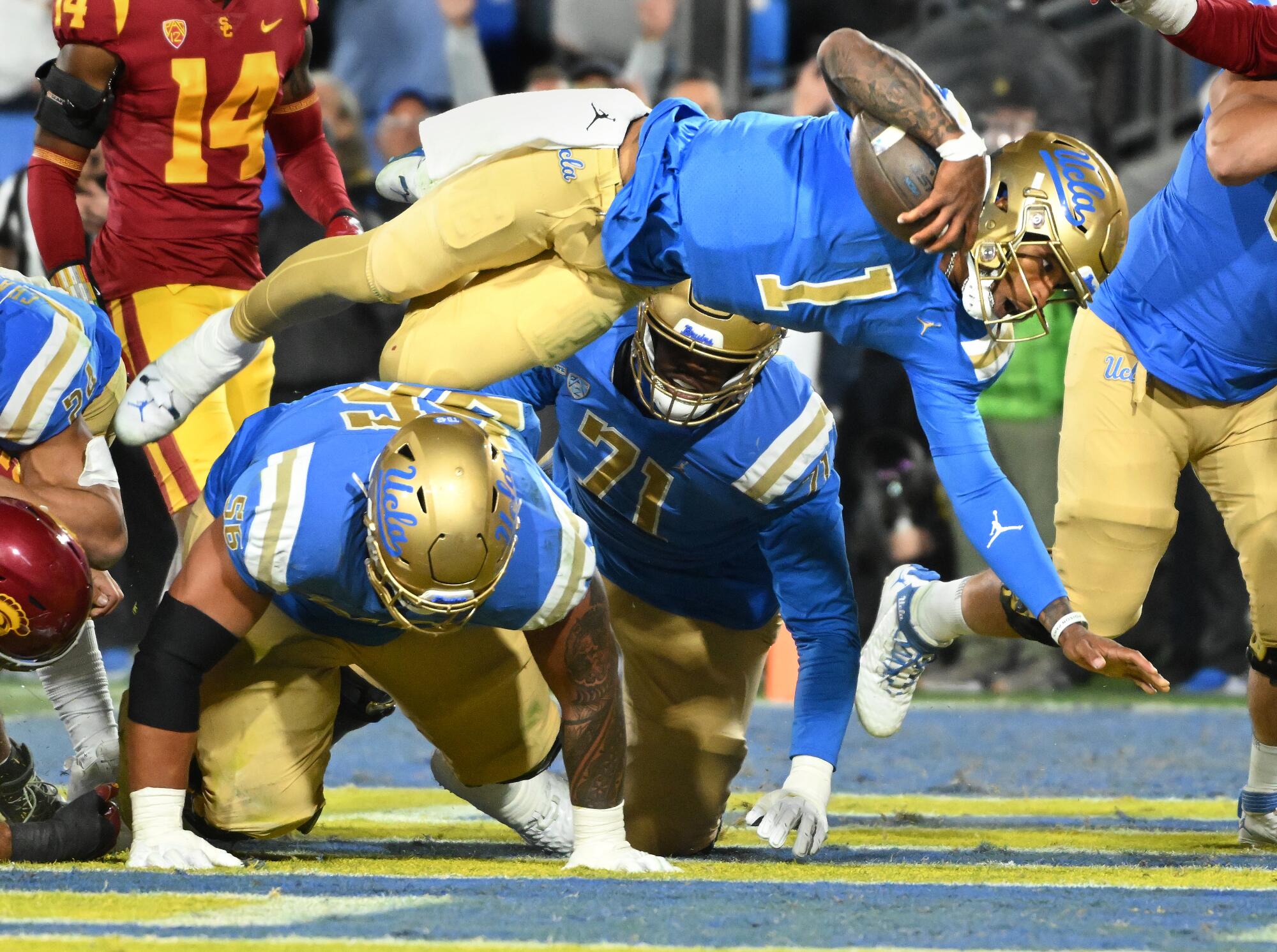 UCLA quarterback Dorian Thompson-Robinson dives over teammates to score a touchdown against USC