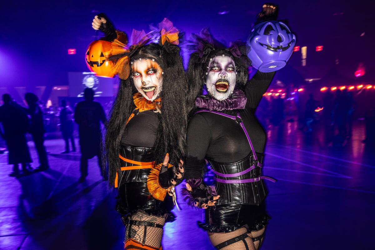 Two people are dressed in Halloween costumes while holding plastic pumpkins