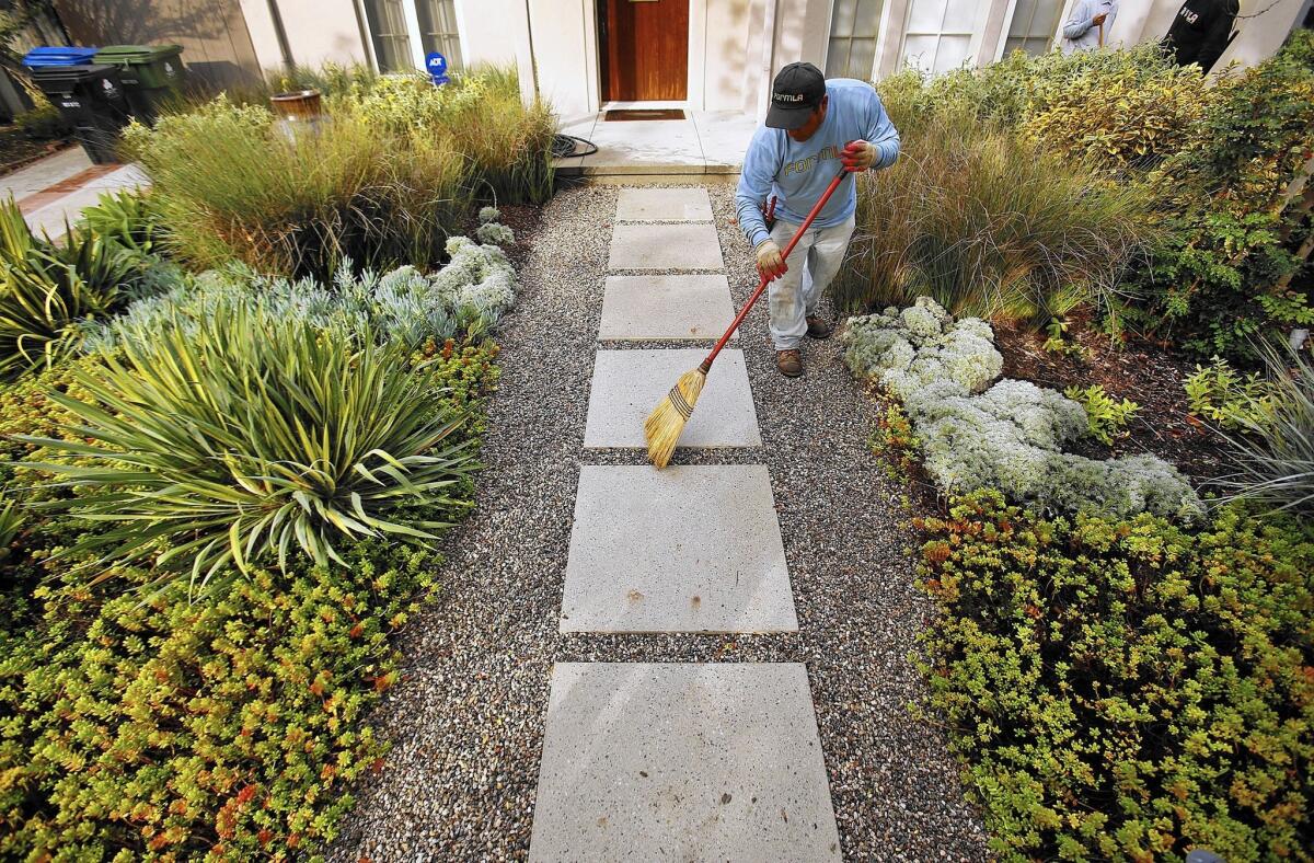 Elias Hernandez, on the maintenance team with landscaping firm FormLA in Tujunga, sweeps the drought-resistant plantings at a Los Angeles client's home.