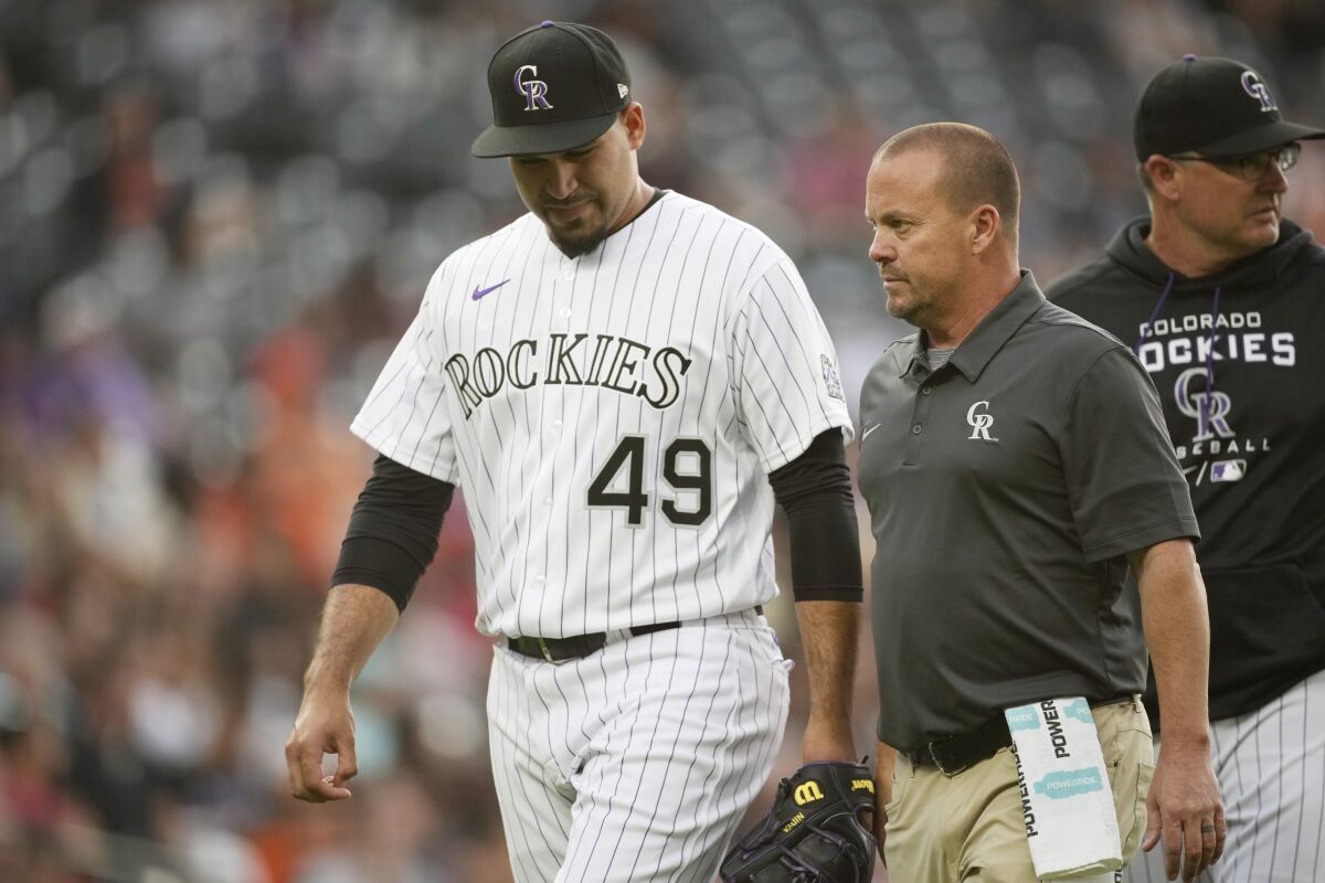 Colorado Rockies starting pitcher Antonio Senzatela, left, is led back to the dugout by assistant trainer Heath Townsend after Senzatela was pulled from the mound before the third inning of a baseball game against the San Francisco Giants, Monday, May 16, 2022, in Denver. (AP Photo/David Zalubowski)