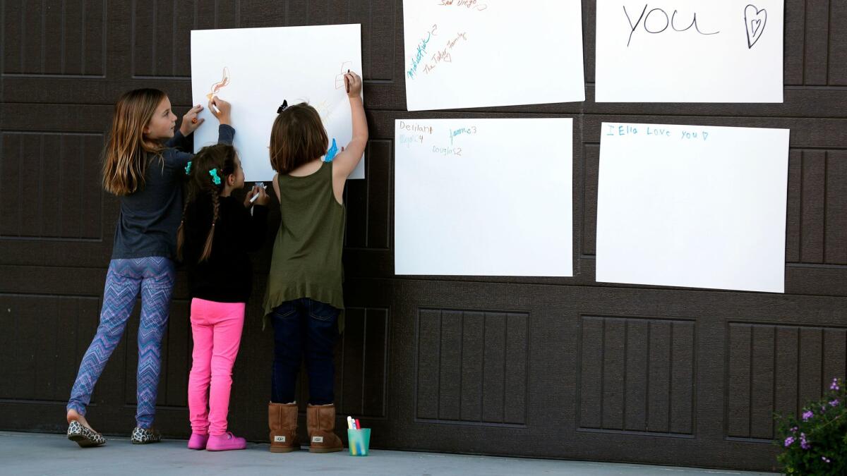 Children write notes of support on a poster in their Perris neighborhood for the 13 Turpin siblings, whose parents have been charged with torturing them.