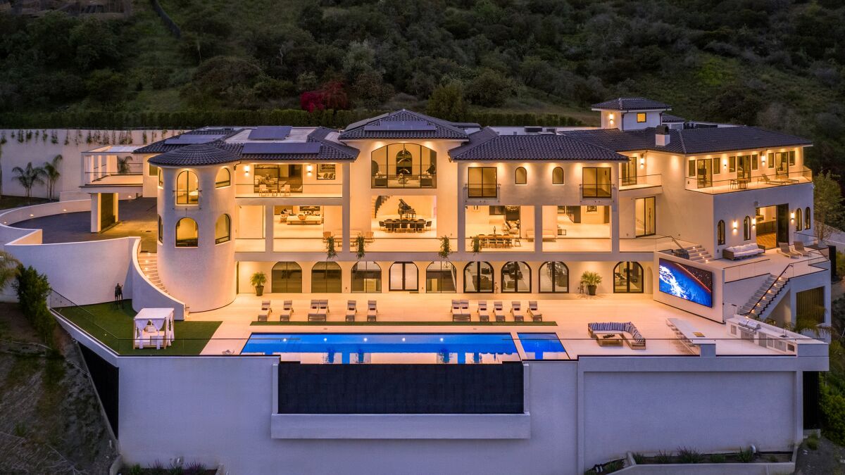 A large, white mansion in the hills of Bel-Air with a deck and infinity pool
