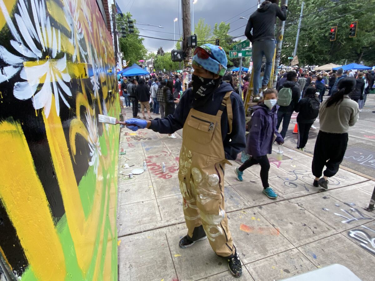 Procter adds a flower to his mural in the area initially dubbed the "Capitol Hill Autonomous Zone."