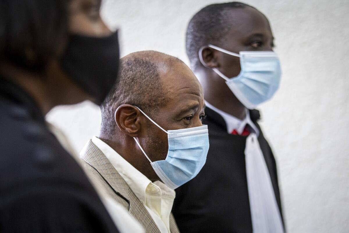 Paul Rusesabagina is flanked by two people, all three in masks.