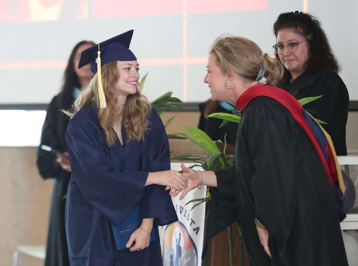 Graduate Vanessa Fultz, left, shakes hands with Michelle Murphy, a member of the Newport-Mesa Unified school board.
