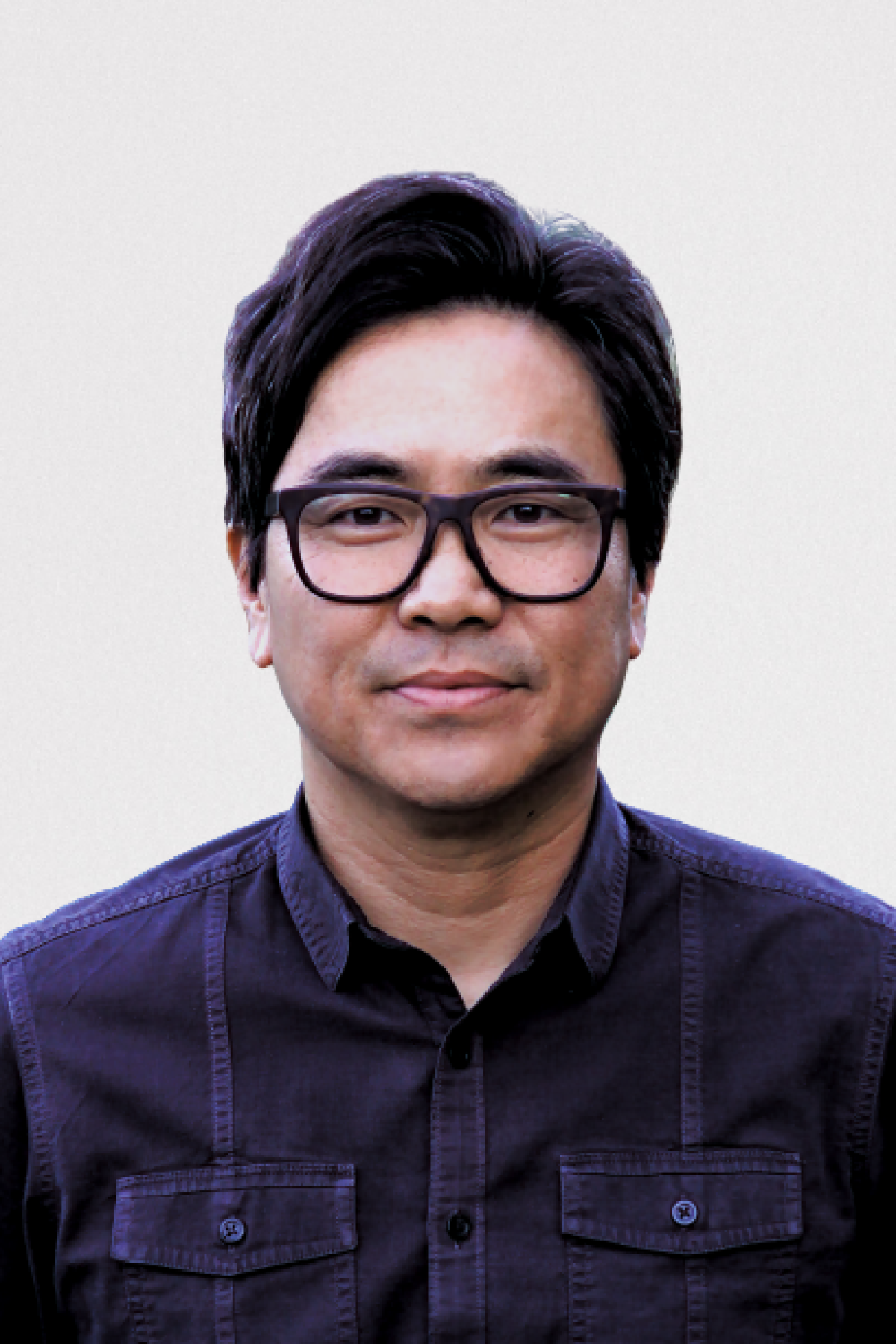 A man wearing glasses and a dark blue collared shirt poses for a portrait photo.