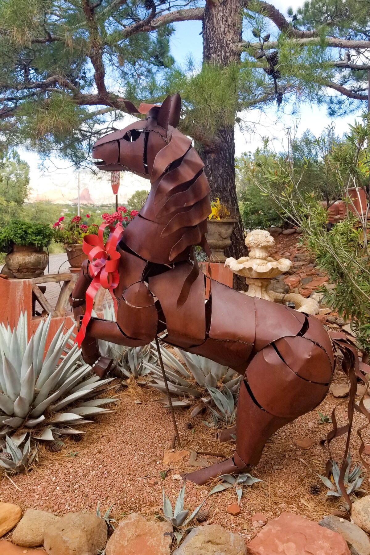A metal sculpture of a rearing horse in a desert garden