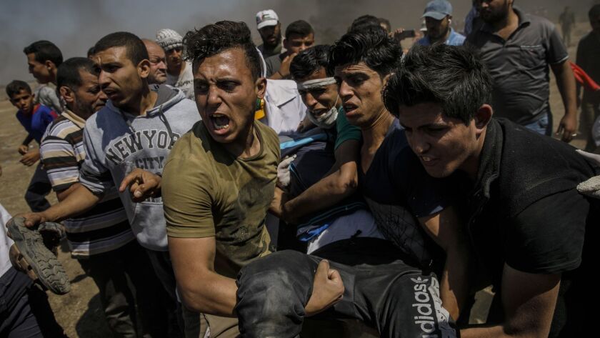 Protesters carry away the wounded shot by Israeli forces as medical units are overwhelmed by casualties on the border fence separating Israel and the Gaza Strip.