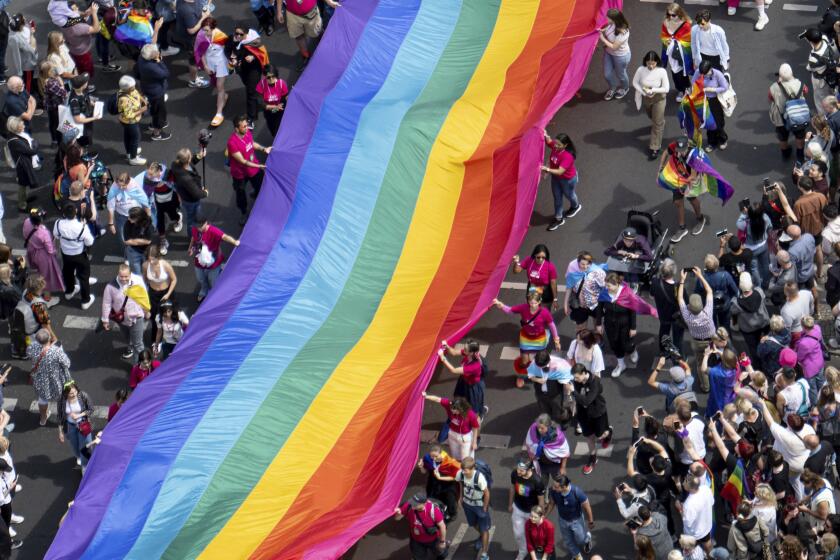 FILE - People hold a rainbow flag as they attend the 45th Berlin Pride Parade for Christopher Street Day (CSD) in Berlin, Germany, Saturday, July 22, 2023. German lawmakers are expected to vote on a government plan to make it easier for transgender, intersex and nonbinary people to change their name and gender in official documents. (Fabian Sommer/dpa via AP, File)