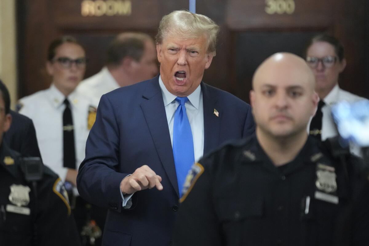 Former President Trump speaks while people in security uniforms stand around him.