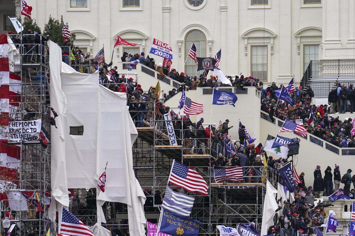 Trump supporters, waving U.S. and Trump flags, storm the U.S. Capitol in Washington.