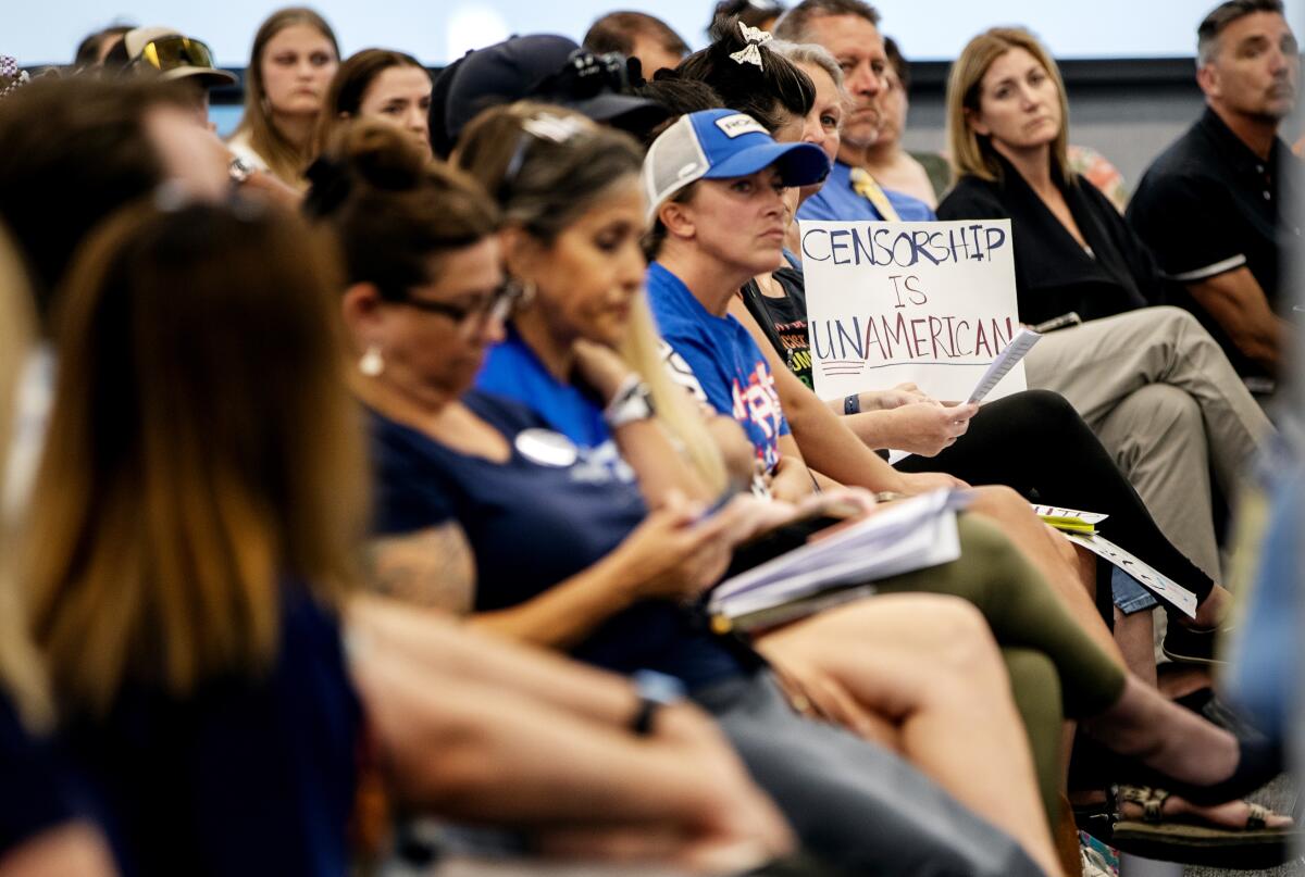 An audience member holds a sign that reads: "Censorship is unAmerican" while sitting in a crowd.