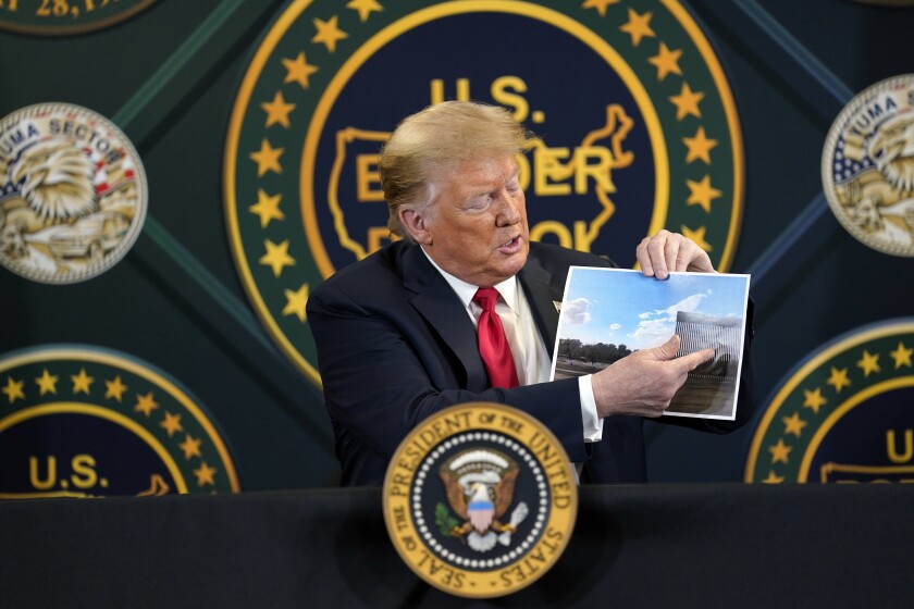 President Trump shows a photo of recently completed sections of border wall during a roundtable Tuesday in Yuma, Ariz.