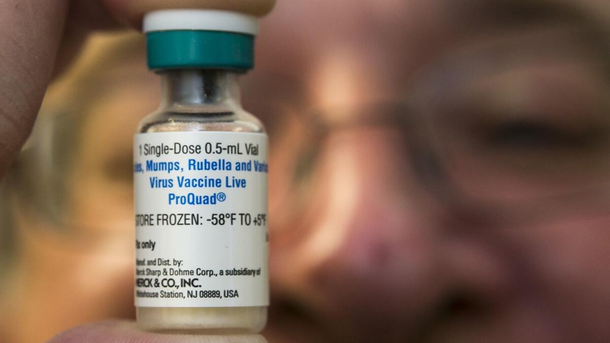 A pediatrician holds a dose of the measles-mumps-rubella (MMR) vaccine at his practice in Northridge, Calif.