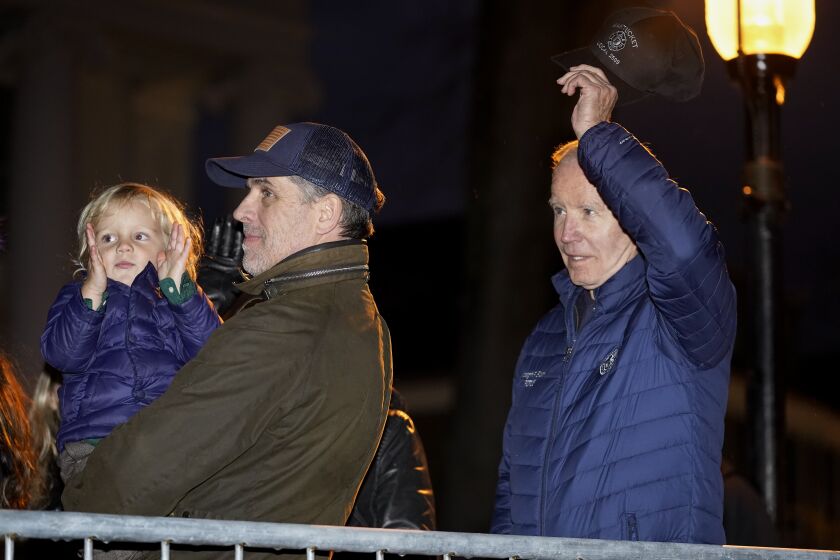 President Joe Biden removes his hat as he is recognized during the annual Christmas Tree Lighting ceremony in Nantucket, Mass., Friday, Nov. 25, 2022. Hunter Biden holds his son Beau Biden at left. (AP Photo/Susan Walsh)
