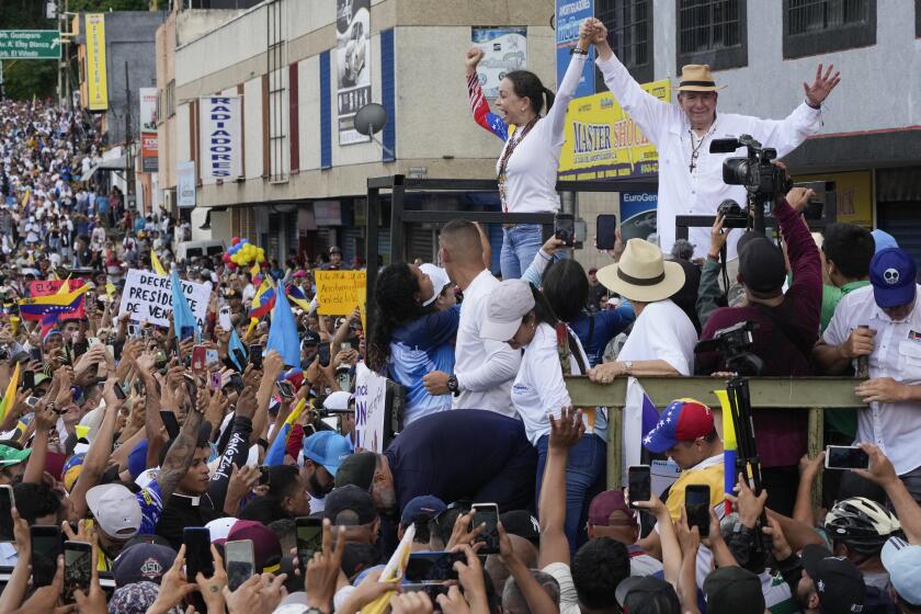 El candidato presidencial venezolano Edmundo González, derecha, y la líder opositora María Corina Machado desfilan en un camión que los transporta entre una multitud de partidarios durante un mitin de campaña en Valencia, Venezuela, el sábado 13 de julio de 2024. (Foto AP/Ariana Cubillos)