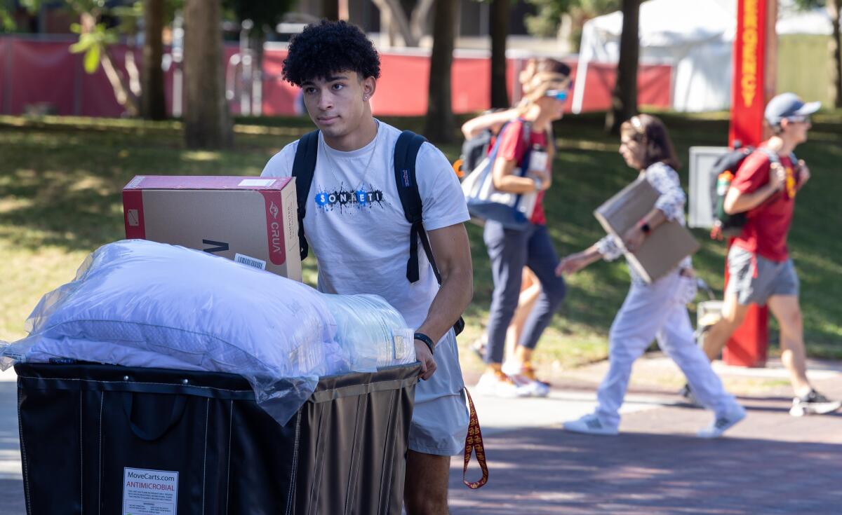 Freshman Joaquin Williams rolls a bin toward his new dorm room.