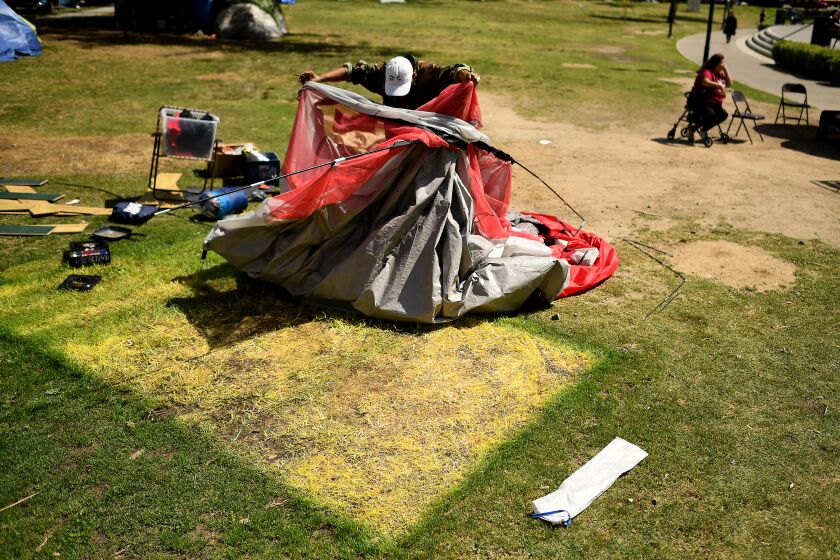 LOS ANGELES CALIFORNIA MARCH 23, 2021-A homeless man tears down his tent before moving out of Echo Park Tuesday. A possible removal of the homeless camp at the park has caused an urgency among the people living there. (Wally Skalij/Los Angeles Times)