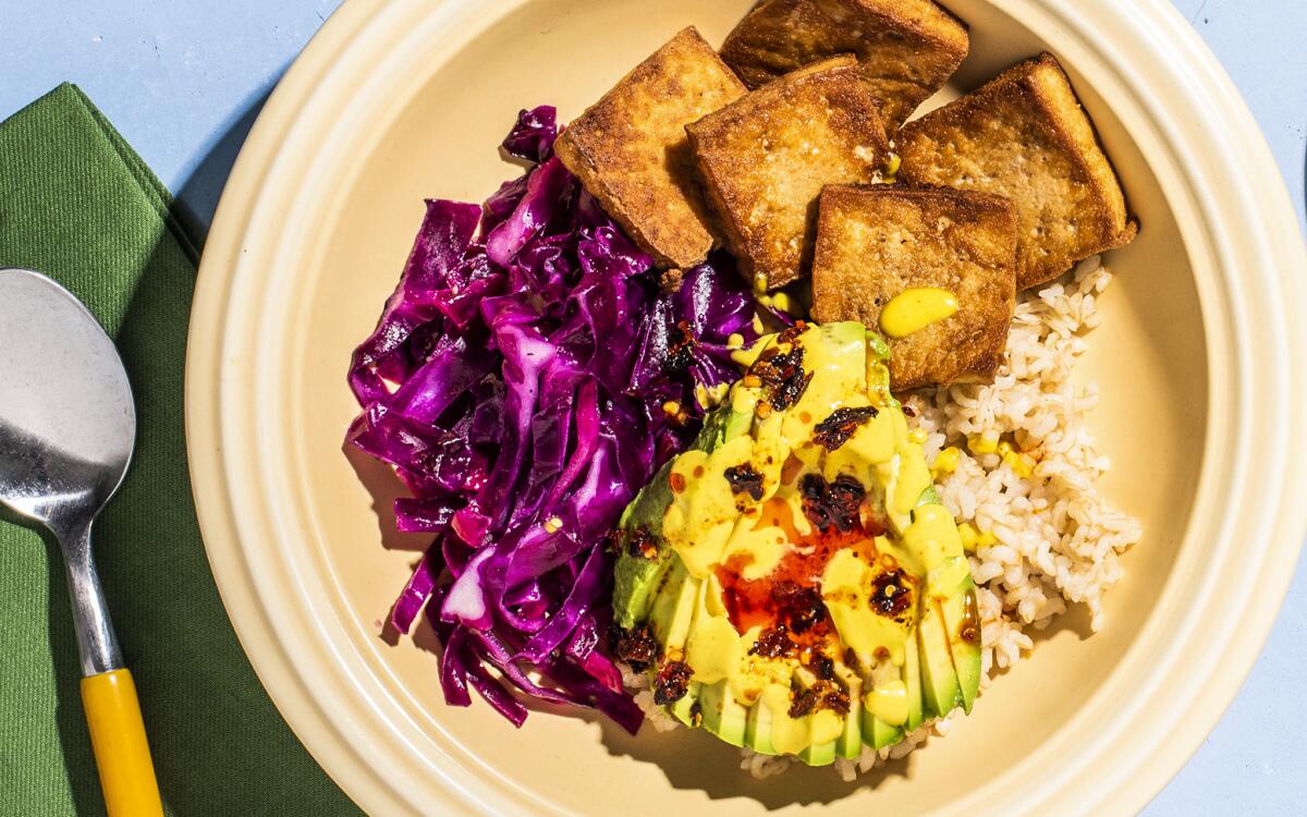 Simply seasoned tofu adds heft to this easy grain bowl tricked out with avocado, turmeric-spiced tahini and chile crisp.