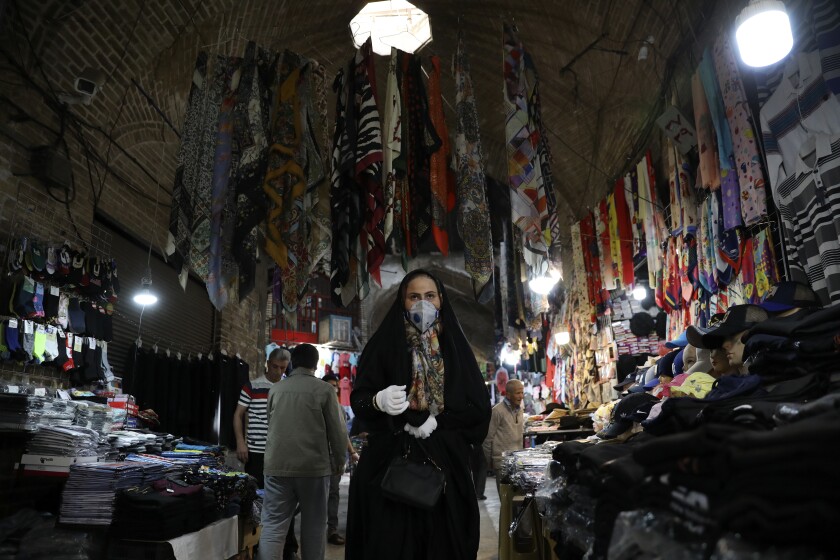 Una mujer con mascarilla y guantes para protegerse del coronavirus camina en el bazar tradicional Qazvin a unos 150 kilómetros (93 millas) del noroeste de Teherán, Irán, el miércoles 22 de abril de 2020. (AP Foto/Vahid Salemi)