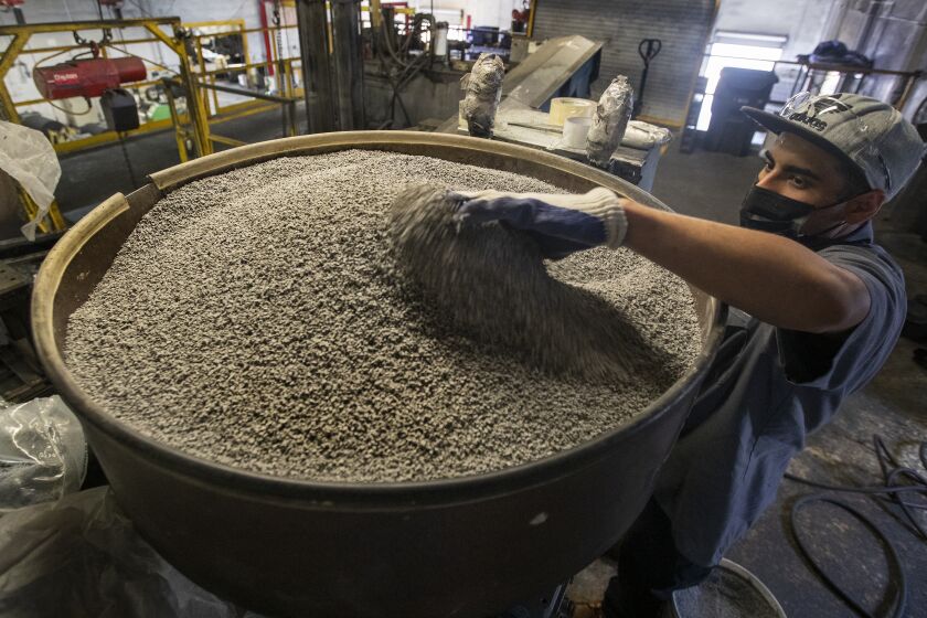COLTON, CA - OCTOBER 04, 2021:Jonathan Contreras, 28, adds gray coloring, to be mixed in with ground up rubber to make rubber tiles at U.S. Rubber Recycling in Colton. Contreras is a former felon. Employers, now facing severe labor shortages, are starting to tap into hiring former felons. U.S. Rubber is a 25 year old company that has been hiring former felons for years. The company makes use of old tires, grinding them into flooring products, including rubber mats for home gyms which have taken off during the pandemic. (Mel Melcon / Los Angeles Times)