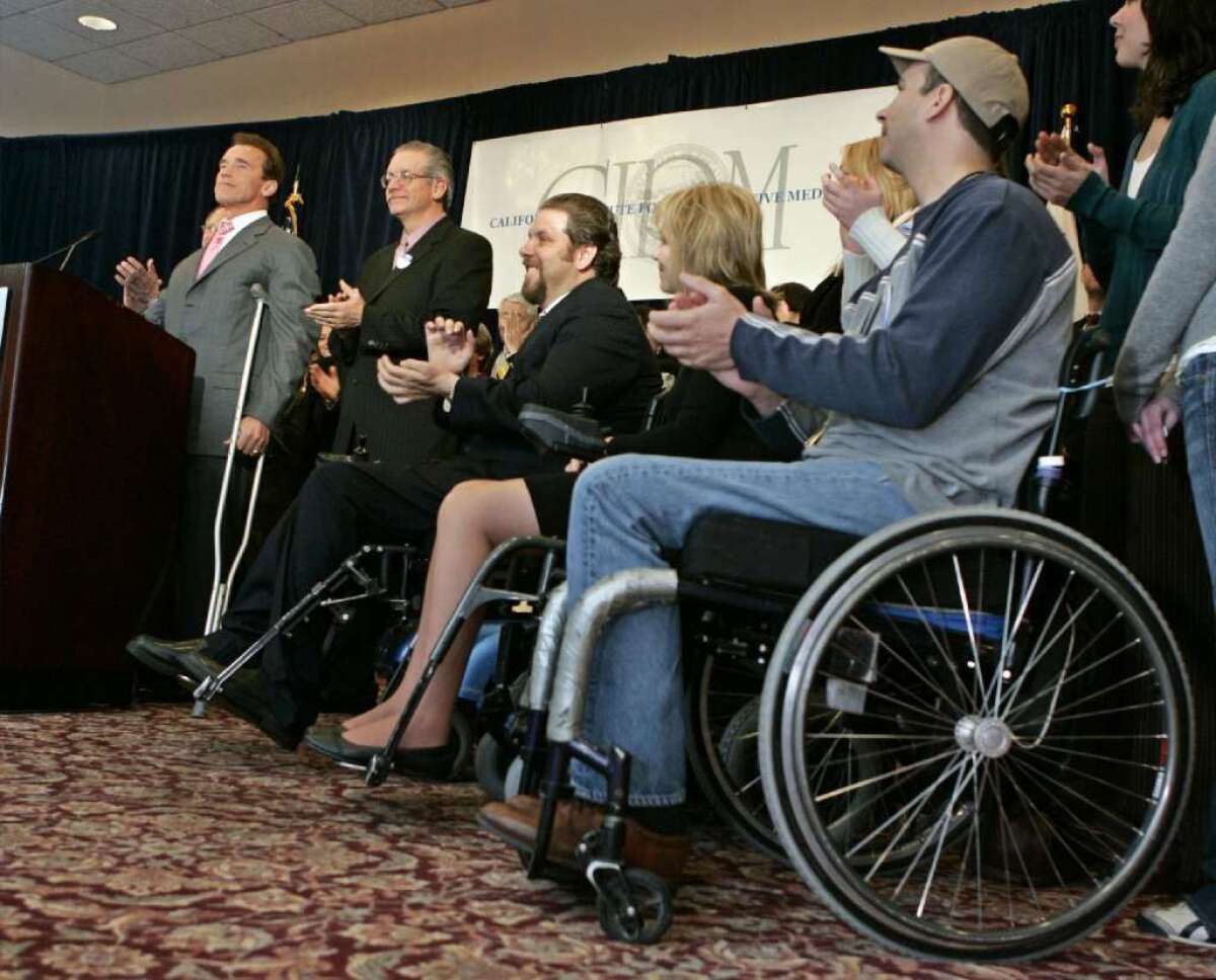 A technique that has been successful in managing Parkinson's disease symptoms could prove useful in helping some people with spinal cord injuries walk again. In this 2007 photo, then-Gov. Arnold Schwarzenegger is flanked by Californians with spinal cord injuries at an event for the California Institute for Regenerative Medicine.