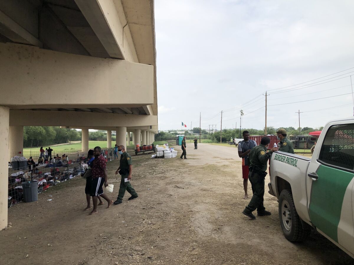 U.S. Customs and Border Protection agents process Haitiain migrants under a border bridge
