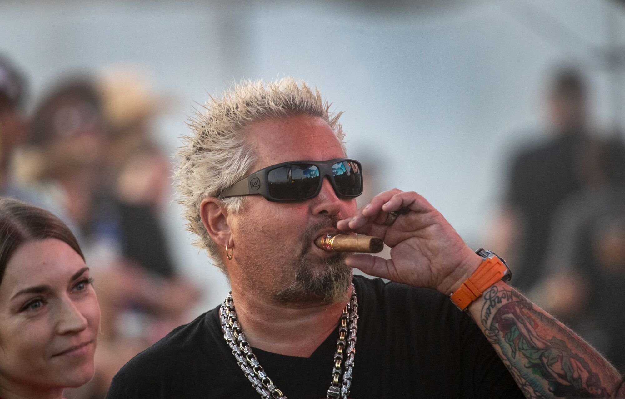 Guy Fieri smokes a cigar while watching Midland perform